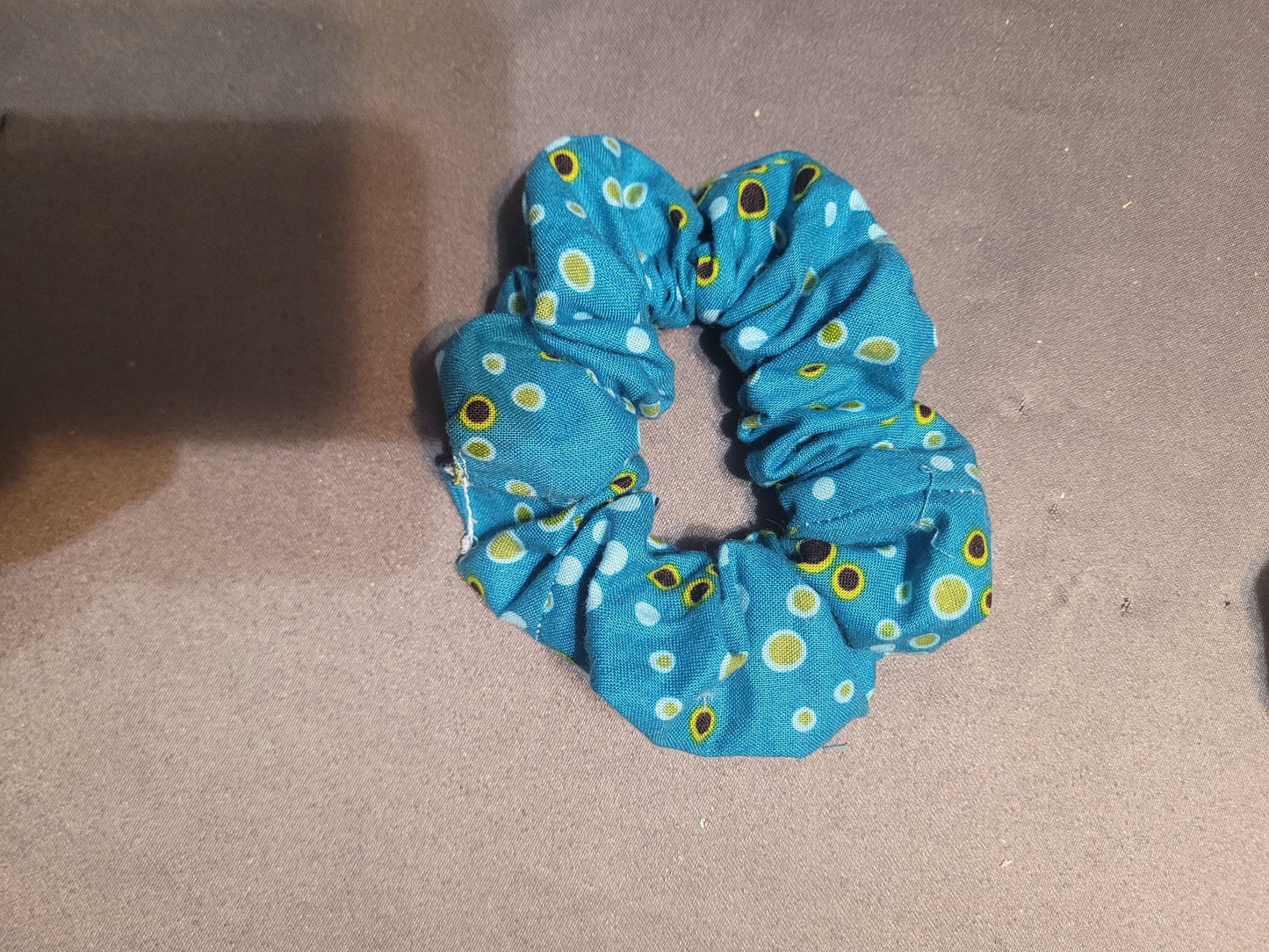 Blue scrunchie with green and black dots.